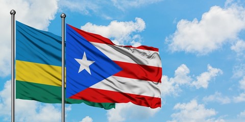 Rwanda and Puerto Rico flag waving in the wind against white cloudy blue sky together. Diplomacy concept, international relations.