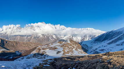 Obraz premium Kazbegi mountains and Gergeti Trinity Church under clouds