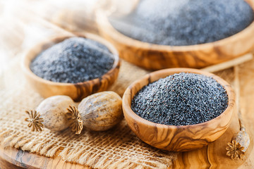 Fresh poppy seeds on white rustic table. Dry poppies heads on old board.