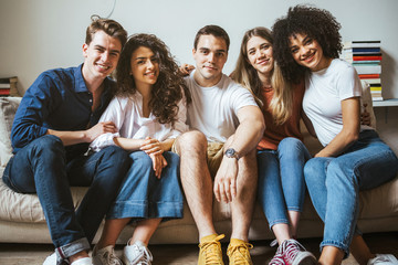 Portrait of a group of friends sitting on the sofa at home - Millennials have fun together in an...