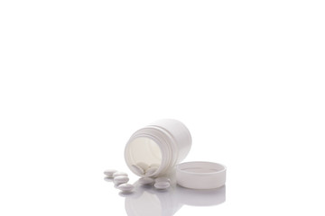 A bottle of pills lies on a mirror surface on a white background in the center with a place for text