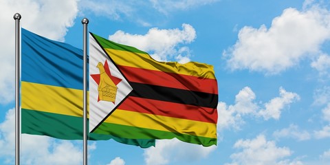Rwanda and Zimbabwe flag waving in the wind against white cloudy blue sky together. Diplomacy concept, international relations.