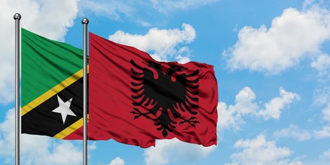 Saint Kitts And Nevis and Albania flag waving in the wind against white cloudy blue sky together. Diplomacy concept, international relations.