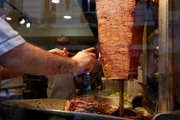 An arm moving to cut the kebab meat