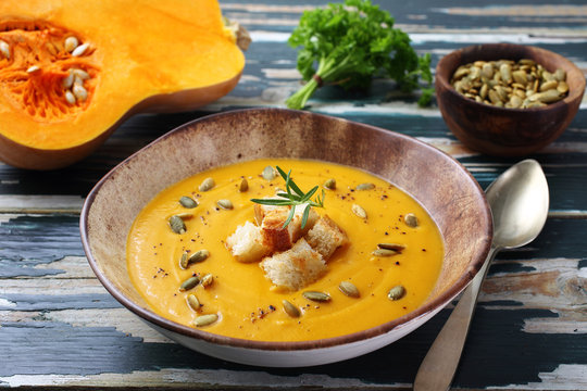 zuppa crema di zucca gialla su tavolo colorato verde rustico