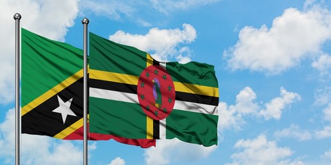 Saint Kitts And Nevis and Dominica flag waving in the wind against white cloudy blue sky together. Diplomacy concept, international relations.