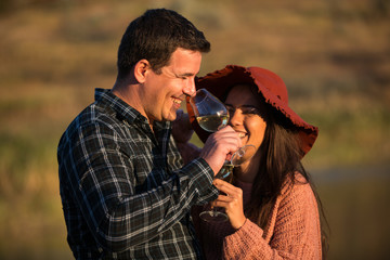 Man and woman with glasses of wine in his hands on the sunset