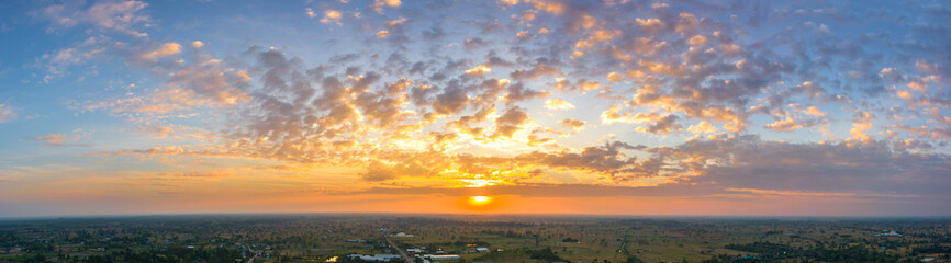 Panorama Sunlight with dramatic sky. Cumulus sunset clouds with sun setting down on dark background.Vivid orange cloud sky.