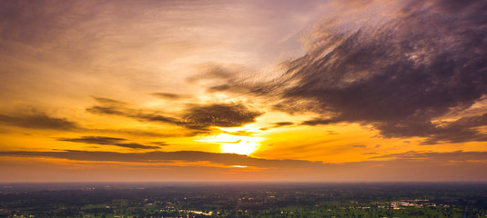 Panorama Sunlight with dramatic sky. Cumulus sunset clouds with sun setting down on dark background.Vivid orange cloud sky.