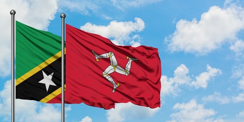 Saint Kitts And Nevis and Isle Of Man flag waving in the wind against white cloudy blue sky together. Diplomacy concept, international relations.