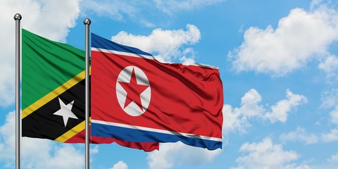 Saint Kitts And Nevis and North Korea flag waving in the wind against white cloudy blue sky together. Diplomacy concept, international relations.