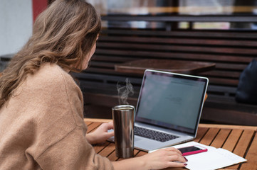 Happy young girl working at a coffee shop with a laptop