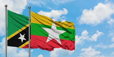 Saint Kitts And Nevis and Myanmar flag waving in the wind against white cloudy blue sky together. Diplomacy concept, international relations.