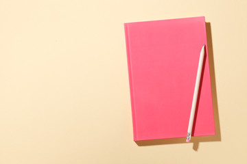 Pink pencil with notebook on background. Place for text