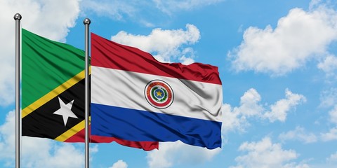 Saint Kitts And Nevis and Paraguay flag waving in the wind against white cloudy blue sky together. Diplomacy concept, international relations.