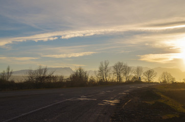 Empty road and mountain range in beams of the evening sun. Russia, North Caucasus, Dagestan, Derbentsky District