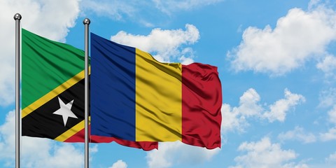 Saint Kitts And Nevis and Romania flag waving in the wind against white cloudy blue sky together. Diplomacy concept, international relations.
