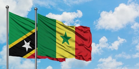Saint Kitts And Nevis and Senegal flag waving in the wind against white cloudy blue sky together. Diplomacy concept, international relations.