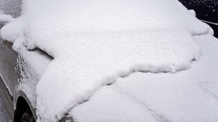 The car, covered with thick layer of snow. Negative consequence of heavy snowfalls. parked cars...