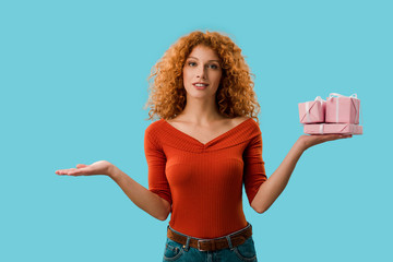 beautiful redhead woman holding gifts isolated on blue