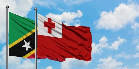 Saint Kitts And Nevis and Tonga flag waving in the wind against white cloudy blue sky together. Diplomacy concept, international relations.