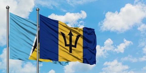 Saint Lucia and Barbados flag waving in the wind against white cloudy blue sky together. Diplomacy concept, international relations.