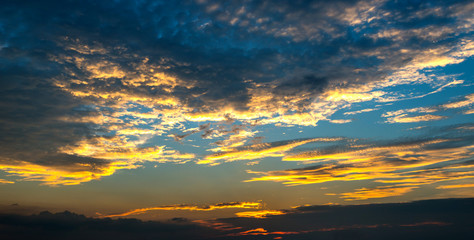 Panorama Sunlight with dramatic sky. Cumulus sunset clouds with sun setting down on dark background.Vivid orange cloud sky.
