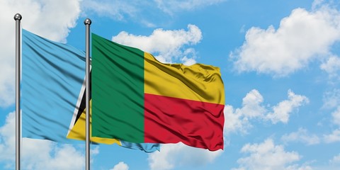 Saint Lucia and Benin flag waving in the wind against white cloudy blue sky together. Diplomacy concept, international relations.