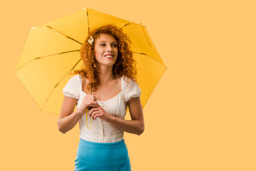 cheerful woman posing with umbrella isolated on yellow
