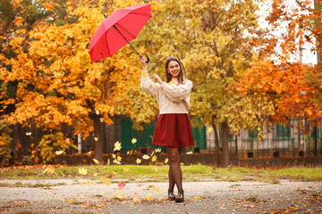 Stylish young woman with umbrella in autumn park