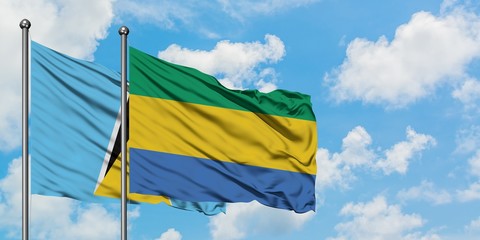 Saint Lucia and Gabon flag waving in the wind against white cloudy blue sky together. Diplomacy concept, international relations.