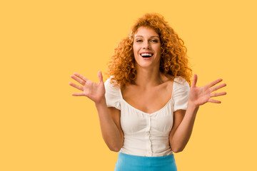 Excited woman with red hair gesturing isolated on yellow
