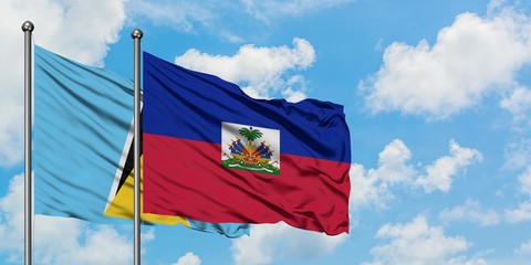 Saint Lucia and Haiti flag waving in the wind against white cloudy blue sky together. Diplomacy concept, international relations.