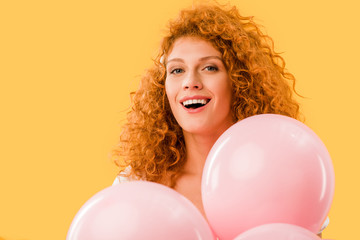 attractive smiling girl with pink balloons isolated on yellow