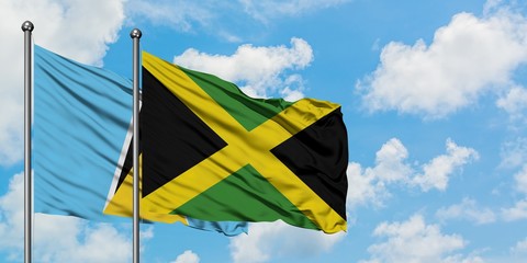 Saint Lucia and Jamaica flag waving in the wind against white cloudy blue sky together. Diplomacy concept, international relations.