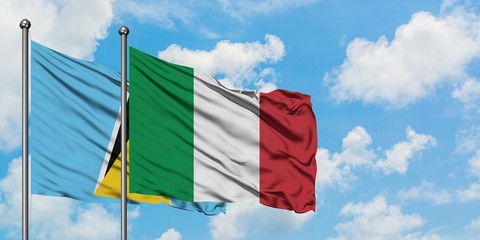 Saint Lucia and Italy flag waving in the wind against white cloudy blue sky together. Diplomacy concept, international relations.