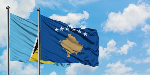 Saint Lucia and Kosovo flag waving in the wind against white cloudy blue sky together. Diplomacy concept, international relations.