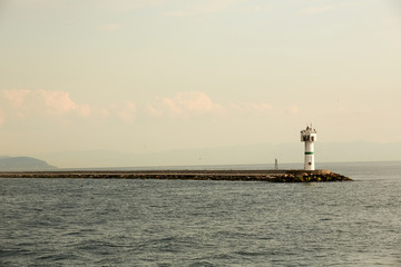 Beautiful seascape with lighthouse. Calm sea and a lighthouse on the pier. Small beacon in the endless sea. Landscape and beacon. Lighthouse