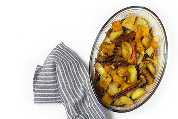 Warm autumn salad with pumpkin, potatoes, carrots on a platter on a white wooden background.