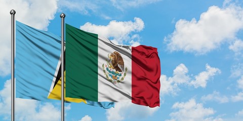 Saint Lucia and Mexico flag waving in the wind against white cloudy blue sky together. Diplomacy concept, international relations.