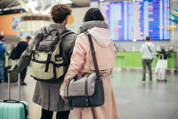 Back view of couple in airtport. Carry purses and suitcase. Ready for trip or vacation. Carry...