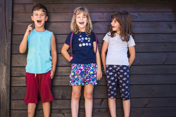 Portrait of two girls, sisters and their boy friend, enjoying summer, smiling and making funny faces. International Childrens Day concept