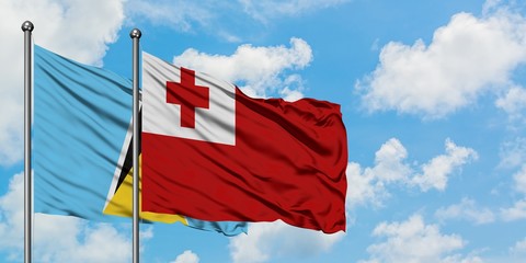 Saint Lucia and Tonga flag waving in the wind against white cloudy blue sky together. Diplomacy concept, international relations.