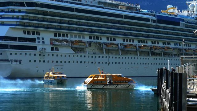 Tender boats are used to get cruise ship passengers to and from shore when docking is not possible. These boats are being used on the fjord at Geiranger, Norway.