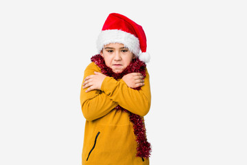 Little boy celebrating christmas day wearing a santa hat isolated going cold due to low temperature or a sickness.