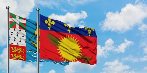 Saint Pierre And Miquelon and Guadeloupe flag waving in the wind against white cloudy blue sky together. Diplomacy concept, international relations.
