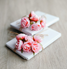 Couple of gift boxes wrapped with simple white craft paper and decorated with bouquet of roses and bunch of eucalyptus.