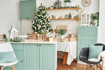 Interior light kitchen with christmas decor and tree. Turquoise-colored kitchen in classic style. Christmas in the kitchen. Bright kitchen in mint and white shades with Christmas. 