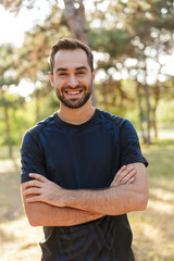 Sports man posing outdoors in nature green park.
