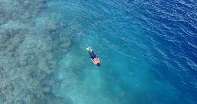 tourist swimming in the ocean, traveler snorkeling in the clear coral reef,  drone